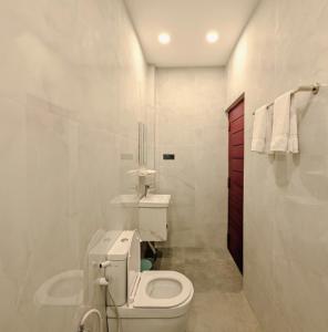 a white bathroom with a toilet and a red door at Kings hotel in Colombo