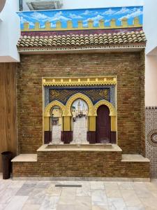 a brick wall with a building with yellow curtains at Hôtel kairouan in Fez
