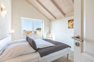 a white bedroom with a bed and a window at Ferienhaus Nordspitze in Dagebüll