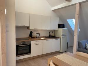 a kitchen with white cabinets and a refrigerator at Apartmán Ve Štítu in Lomnice nad Popelkou +1 photo