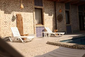two chairs and a swimming pool next to a building at Hotel Old Heritage in Tashkent