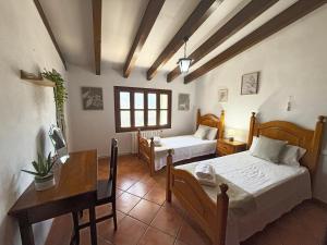 a bedroom with two beds and a table and a desk at Sa Màniga in Fornalutx +24 photos
