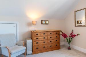 a bedroom with a dresser and a chair and a vase of flowers at 1 Bed in Mortehoe oc-barri in Mortehoe