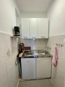 a small kitchen with white cabinets and a sink at Apartments Hrnjić in Umag +68 photos