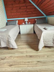 two beds in a room with a wooden ceiling at Nõva Külalistemaja in Nõva