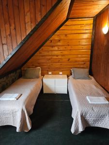 two beds in a attic room with wooden walls at Nõva Külalistemaja in Nõva