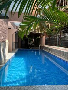 a large blue swimming pool with a palm tree at Bliss By Stays,Calangute in Calangute