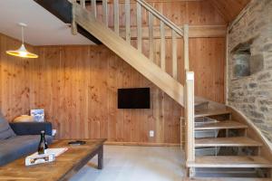 a living room with a wooden staircase and a tv at Gite des Hauts Grève - Penty in Saint-Michel-en-Grève