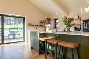 a kitchen with a green island with bar stools at Easter Kincaple Garden Cottage in St. Andrews