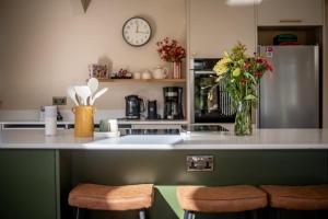 a kitchen with a counter with two stools and a refrigerator at Easter Kincaple Garden Cottage in St. Andrews +20 photos