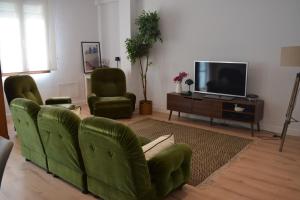 a living room with two green chairs and a flat screen tv at OE concept in Guernica y Luno