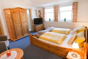 a bedroom with a large bed and a television at Zum Fahrensmann in Norddorf