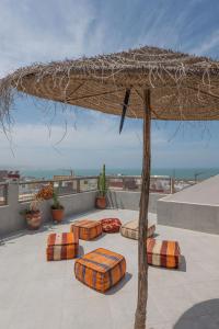 a seating area with pillows and a straw umbrella at Imsouane Sea surf Camp in Imsouane