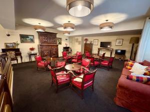 a living room with red chairs and tables and a piano at Hôtel Saint Sébastien in Lourdes