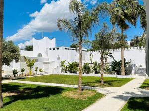 a white building with palm trees and a sidewalk at Villa Oasis Hammamet in Hammamet