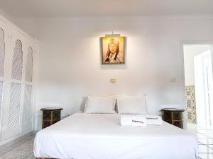 a bedroom with a white bed with a picture on the wall at Villa Oasis Hammamet in Hammamet +21 photos