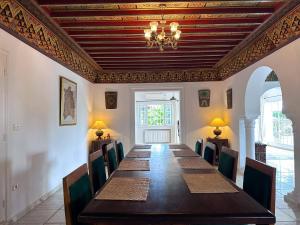 a dining room with a long table and a chandelier at Villa Oasis Hammamet in Hammamet
