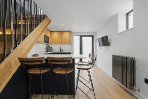 a kitchen with a bar with chairs and a staircase at Stay in Style, Two Bed! in Appleford