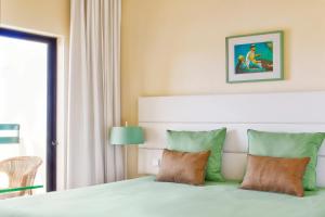 a bedroom with a bed with green and orange pillows at Ondamar Hotel Apartamentos in Albufeira +15 photos