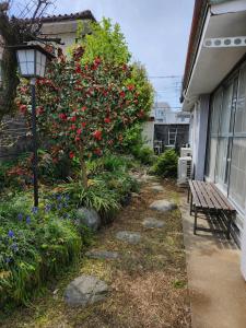 a garden with a tree with red flowers next to a building at Guesthouse Face to Face in Fujinomiya