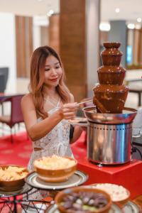 a woman is standing at a table with food at Movenpick Suriwongse Hotel Chiang Mai in Chiang Mai +116 photos
