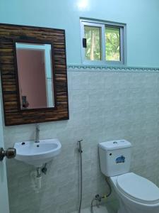 a bathroom with a toilet and a sink and a mirror at Ngak-Ngak Beach Resort in Calatrava