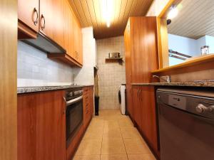 a small kitchen with wooden cabinets and a dishwasher at AC Apartaments Sol Tarter in El Tarter