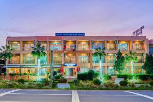 a building with palm trees in front of a street at Hôtel Imi Plage in Agadir