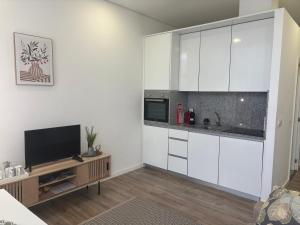 a kitchen with white cabinets and a flat screen tv at AnaSol2 in Esposende