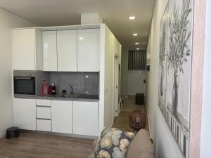 a kitchen with white cabinets and a couch in a room at AnaSol2 in Esposende +6 photos
