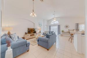a living room with two blue couches and a kitchen at Orlando Theme Park Pool Homes in Kissimmee
