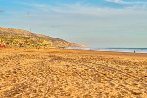 a sandy beach with people walking on the beach at Hôtel Imi Plage in Agadir