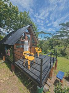 a woman standing on the porch of a tiny house at Cabañas tipo glamping in Moniquirá