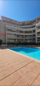 a large building with a swimming pool in front of it at Studio Golfe Juan bord de mer - parking & piscine in Vallauris