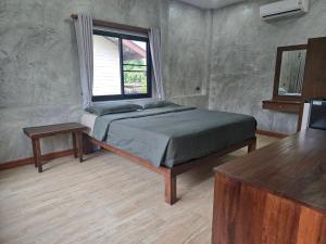 a bedroom with a bed and a window and a table at Cocoa Hut in Mae Chan