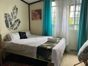 a bedroom with a bed and two windows at D's FarmStay in Kajiado