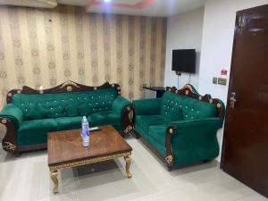 a living room with two green couches and a coffee table at Hotel Lords Inn in Lahore