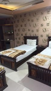 a bedroom with two beds and a wall at Hotel Lords Inn in Lahore