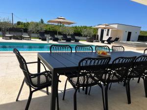 a black table and chairs next to a pool at Villa DEL SOLE with Heated Saltwater Pool, Jacuzzi and Sauna in Ljubuški