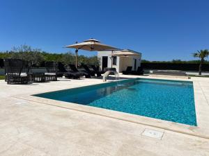 a swimming pool with an umbrella and chairs at Villa DEL SOLE with Heated Saltwater Pool, Jacuzzi and Sauna in Ljubuški