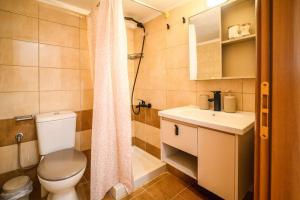 a bathroom with a toilet and a sink and a shower at Coastal nest in Perea +23 photos