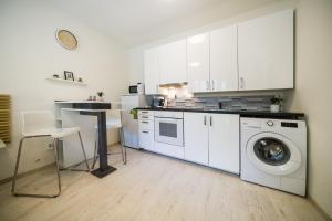 a kitchen with white cabinets and a washing machine at Apartia Urban Station in Brno