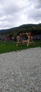 a wooden swing set on a field with a gravel at Domek W Sercu Gór in Ochotnica Górna