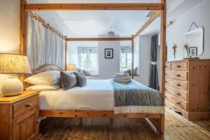 a bedroom with a canopy bed and a dresser at Potter's Wheel, by the lake in High Nibthwaite