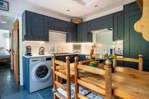 a kitchen with a wooden table and a washing machine at Potter's Wheel, by the lake in High Nibthwaite
