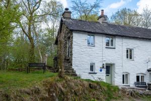 a white house with a bench in front of it at Potter's Wheel, by the lake in High Nibthwaite