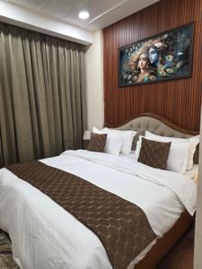 a bedroom with a large bed with a painting on the wall at Ganges Abode in Haridwār