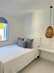 a white bedroom with a bed and a window at Casa El Eden in Puerto Triunfo
