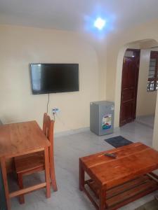 a living room with a table and a tv on the wall at Kibwezi Penthouse in Libwezi