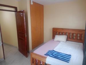 a bedroom with a wooden bed and a wooden cabinet at Kibwezi Penthouse in Libwezi